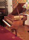 A 1961, Steinway Model M grand piano with a satin, walnut case and spade legs. Piano has an eighty-eight note keyboard and a two-pedal lyre.